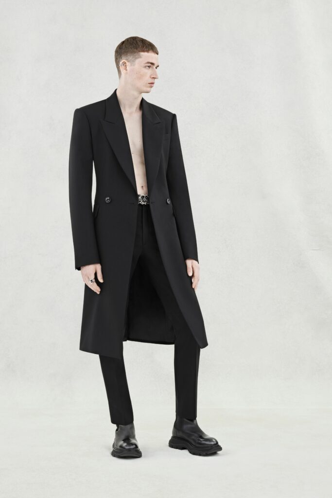 A tailored black wool coat with long sleeves and a collared design, paired with matching pants.