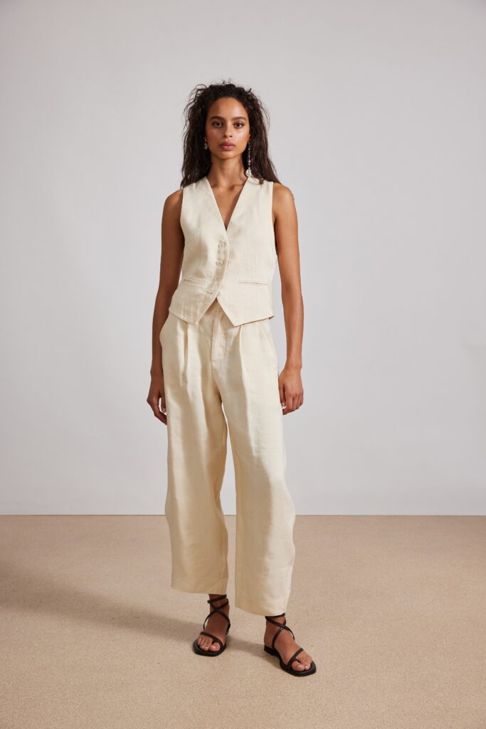 A relaxed beige linen sleeveless vest paired with wide-leg pants for a chic look.