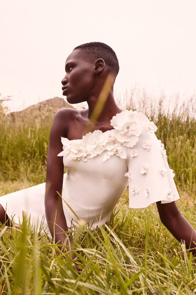 A fitted white silk dress with an off-shoulder design and embroidered floral details.