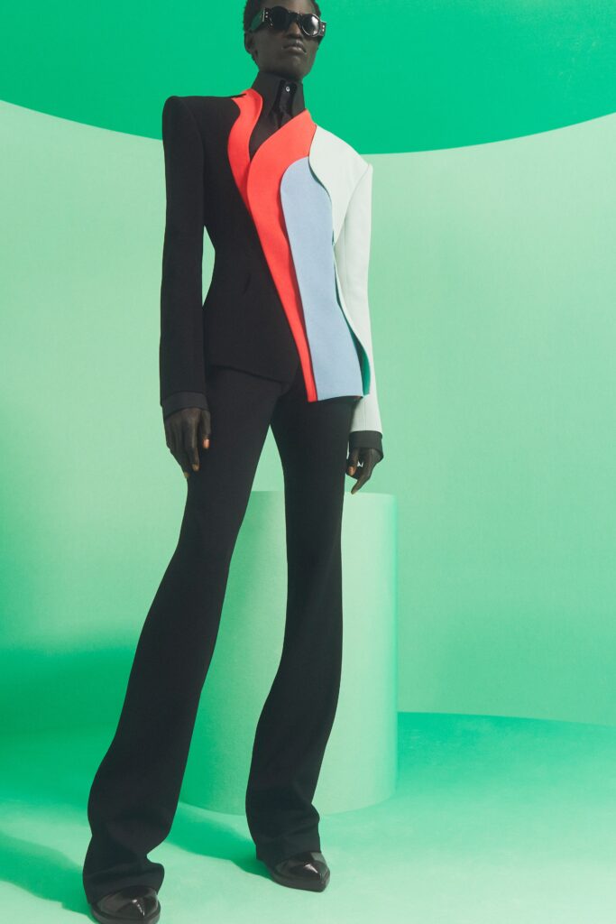 A fitted suit featuring an asymmetric design with color-blocking in black, red, and blue.