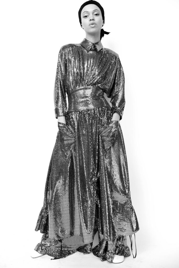 A relaxed silver sequin dress with long sleeves and a collared neckline featuring a tiered design.