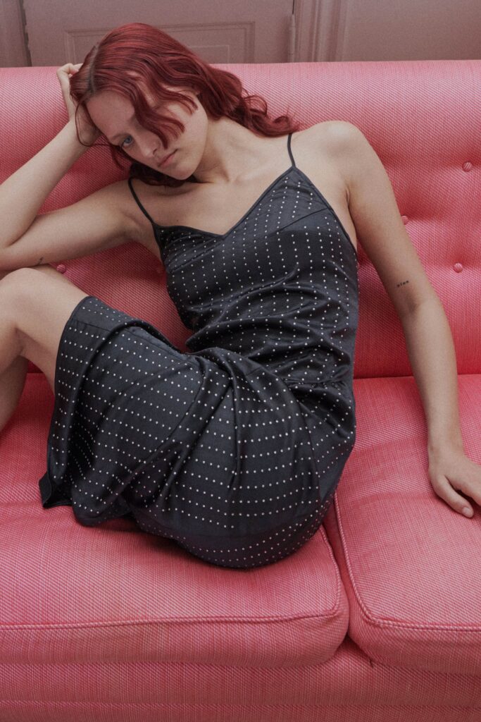 A fitted black silk sleeveless dress with a V-neckline and draped design.