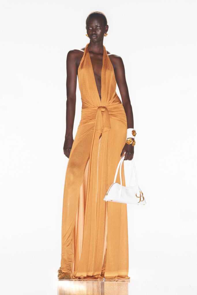 A fitted orange silk dress with a deep V-neckline and a high slit.