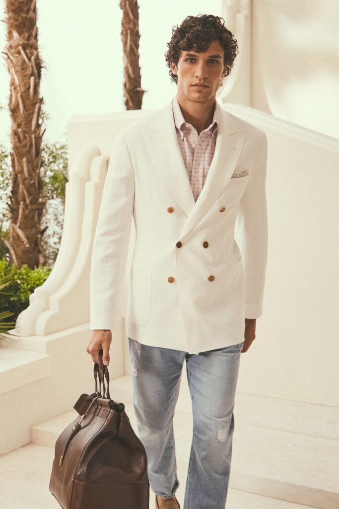 A tailored white blazer with long sleeves, paired with blue straight-leg pants.