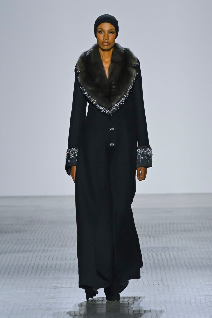 A fitted black wool coat with a fur collar and embroidered details.