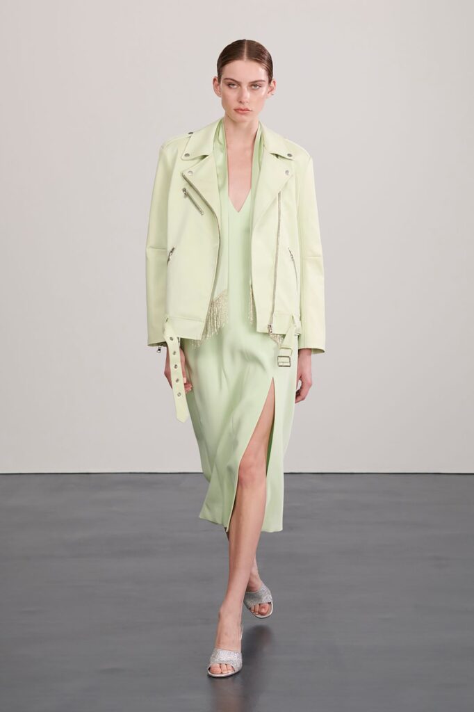 A fitted green silk dress with a V-neckline and slit, paired with a black leather jacket.