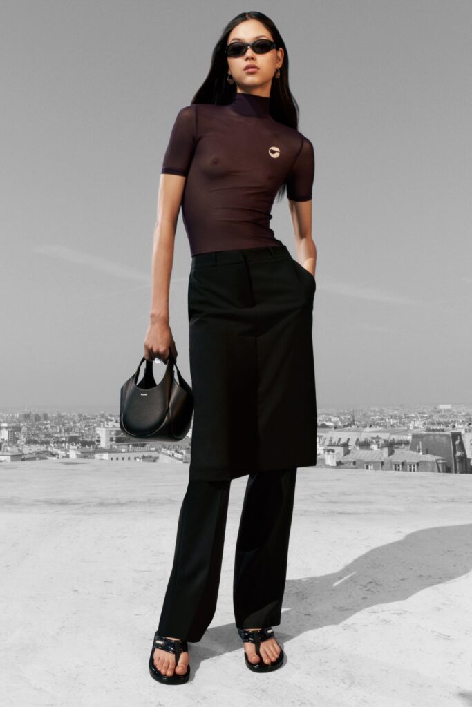 A fitted brown short-sleeve top with a high-neck paired with straight-leg black pants.
