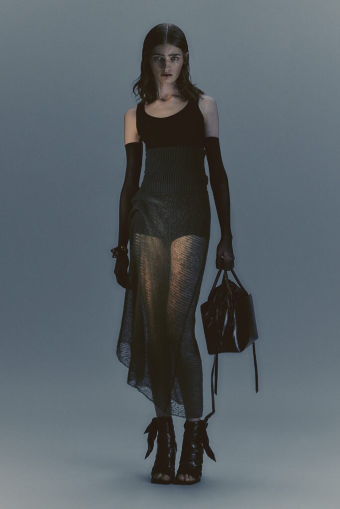 A fitted black sheer dress with a high neckline and asymmetric design.