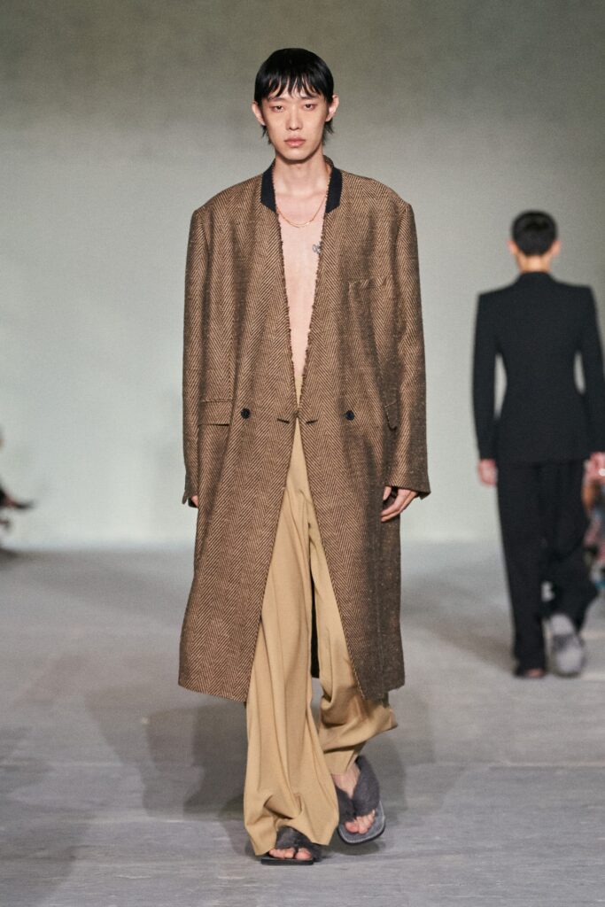 A relaxed brown wool coat with a collared neckline paired with wide-leg beige pants.