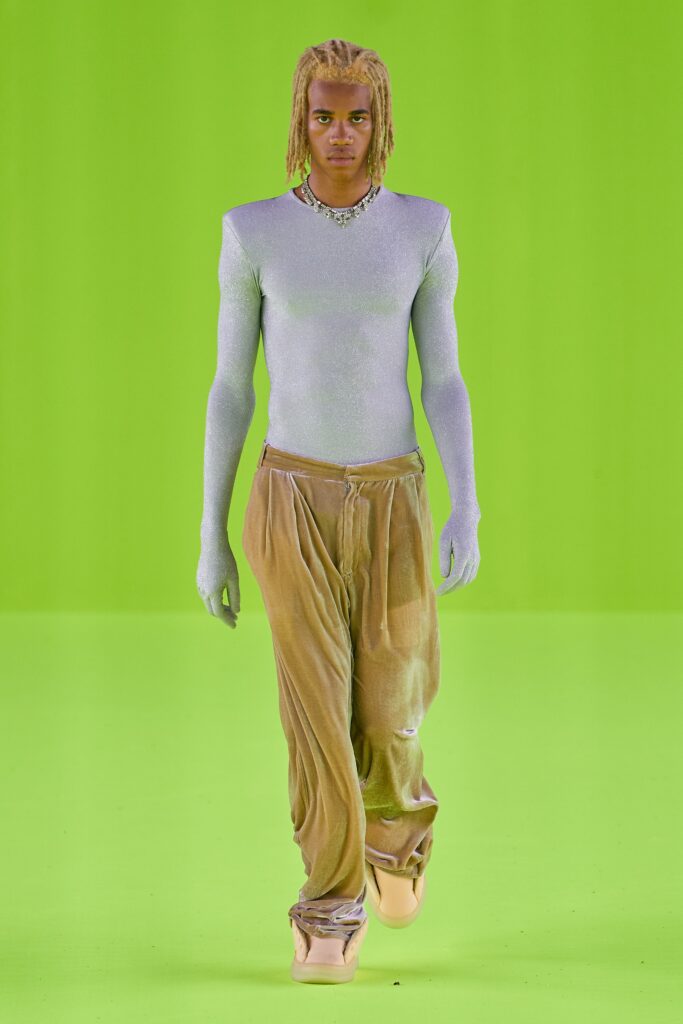 A relaxed purple silk long-sleeve top paired with beige velvet pants featuring an asymmetric design.