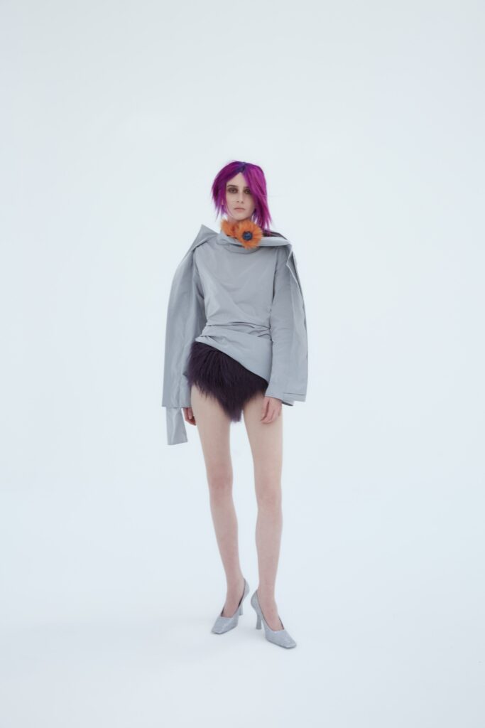 A fitted gray long-sleeve top with a high-neck and an asymmetric fringed black skirt.