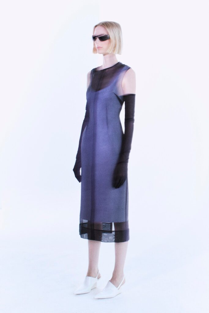 A fitted blue silk dress with a high neckline and sheer detailing.