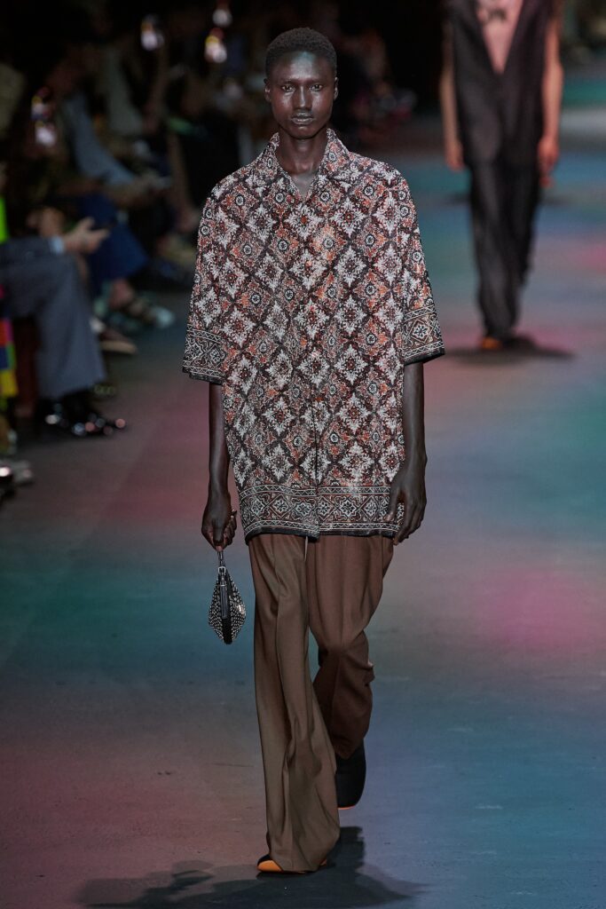 A relaxed-fit multicolor printed shirt paired with brown pants for a stylish look.