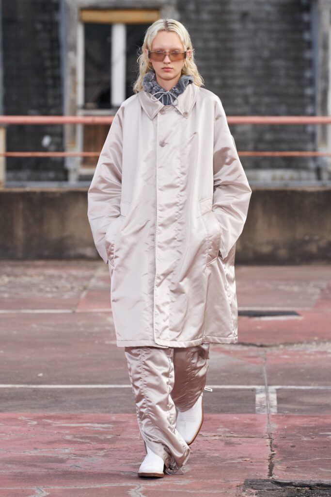 A relaxed beige silk coat with long sleeves and zippered details.