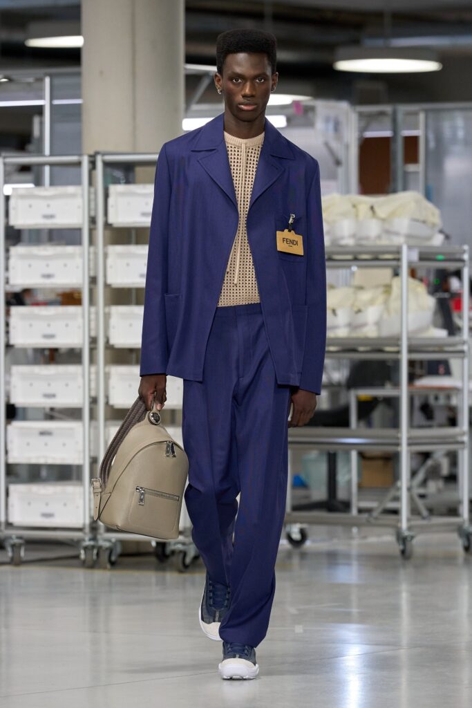 A tailored blue cotton suit with long sleeves and a collared shirt, featuring buttoned details.