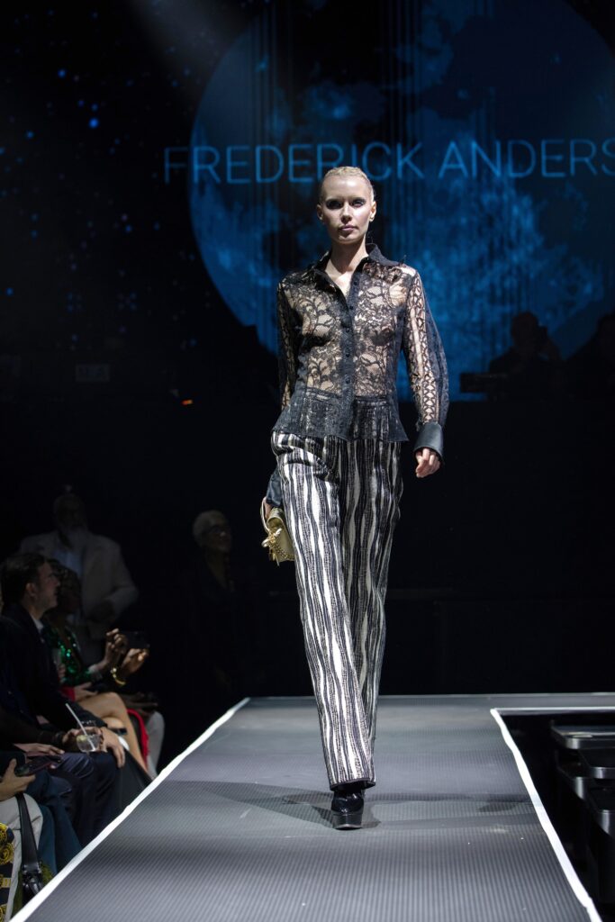 A fitted black lace long-sleeve shirt with a collared neckline paired with silver striped pants.