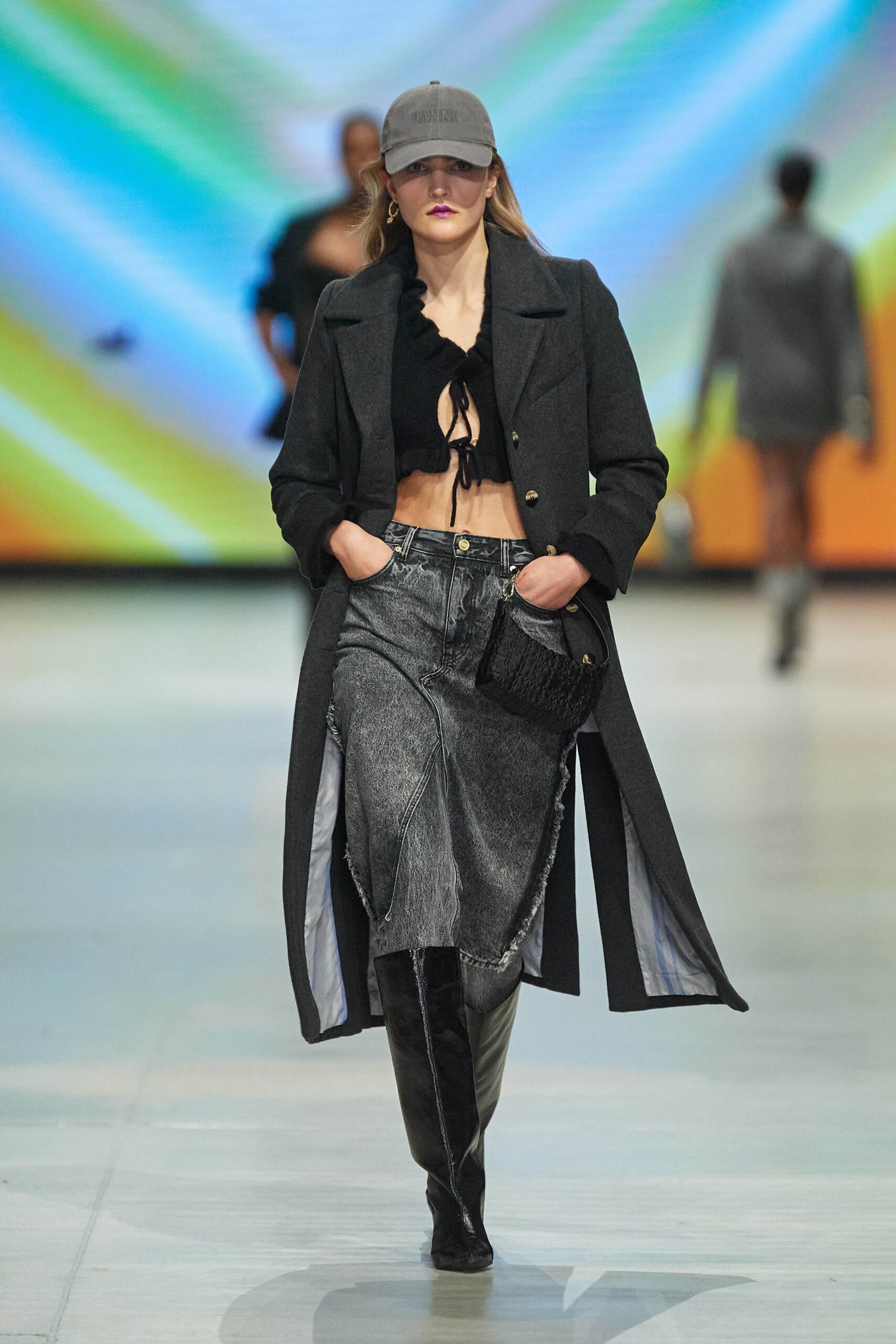 A fitted black wool coat paired with gray asymmetric denim pants, featuring a collared design.