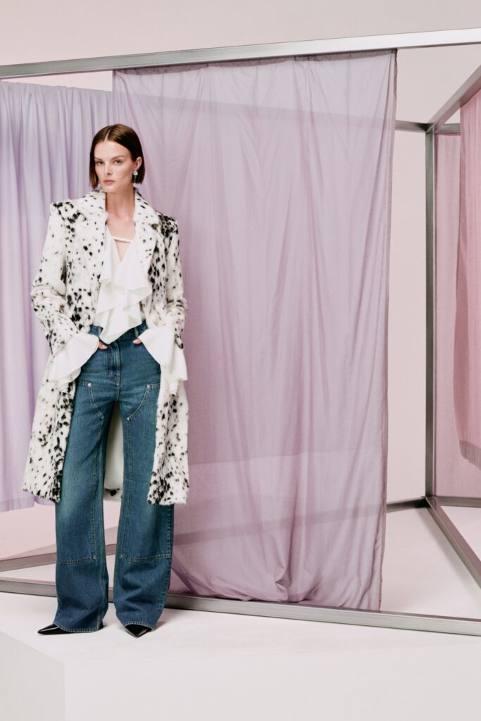 A relaxed-fit black and white ruffled coat paired with wide-leg denim jeans.