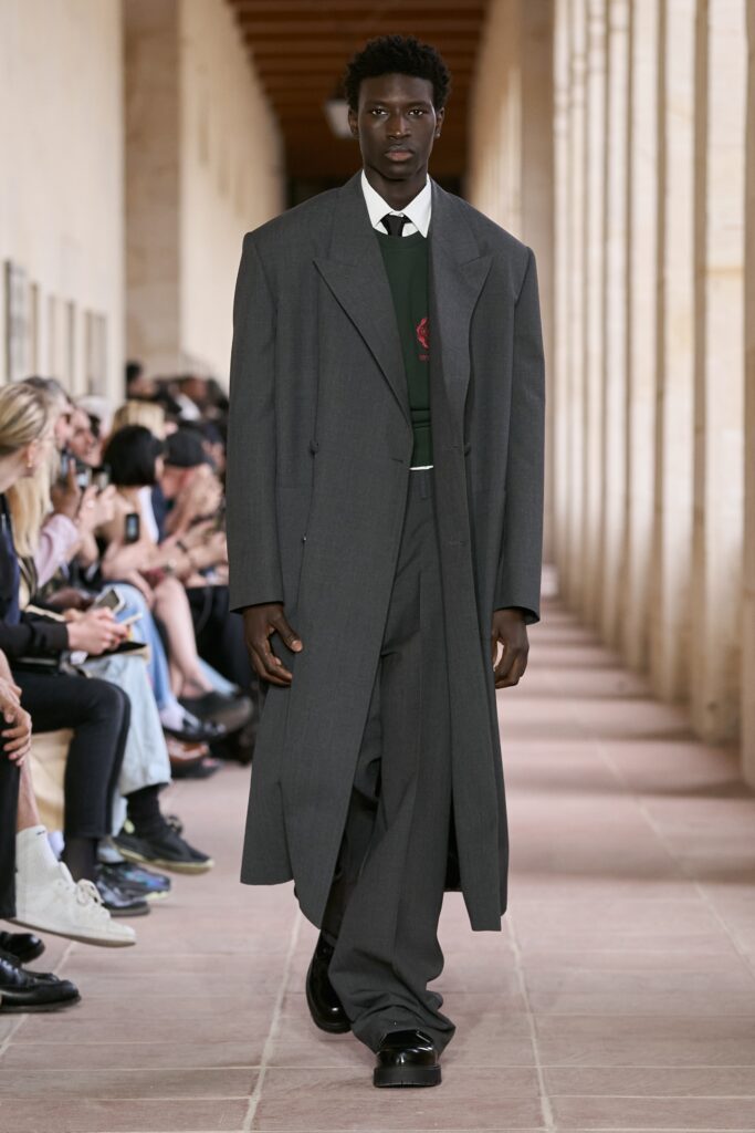 A relaxed gray wool coat paired with straight-leg pants and a collared shirt.