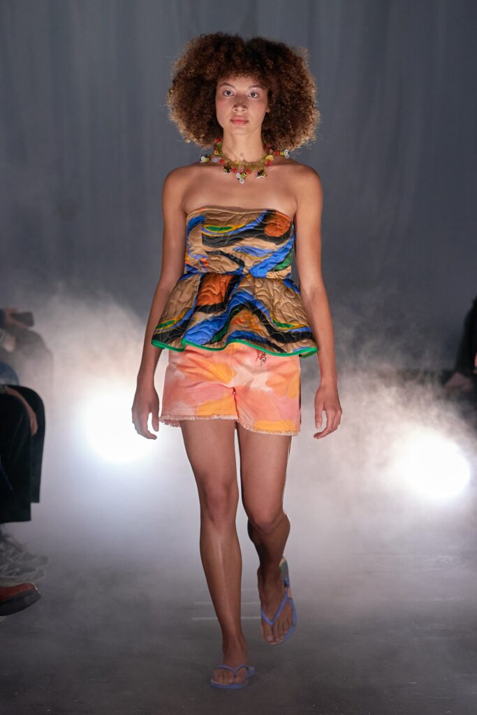 A fitted multicolor sleeveless top paired with high-waisted orange shorts, featuring a layered design.