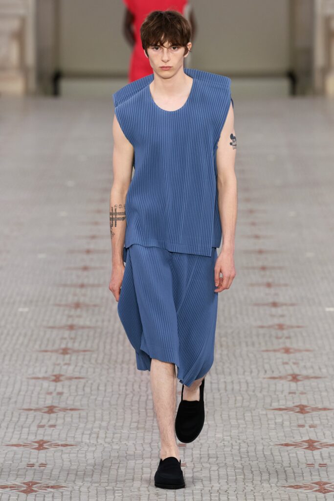 A relaxed blue sleeveless top paired with pleated pants, creating a modern silhouette.