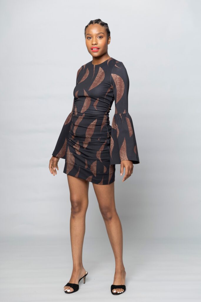 A fitted black cotton dress with long sleeves, a V-neckline, and ruched detailing.