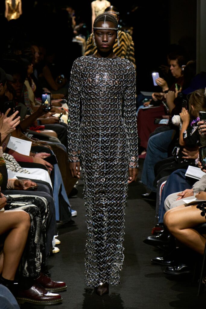 A fitted silver metallic dress with long sleeves and a high neckline, showcasing a straight silhouette.