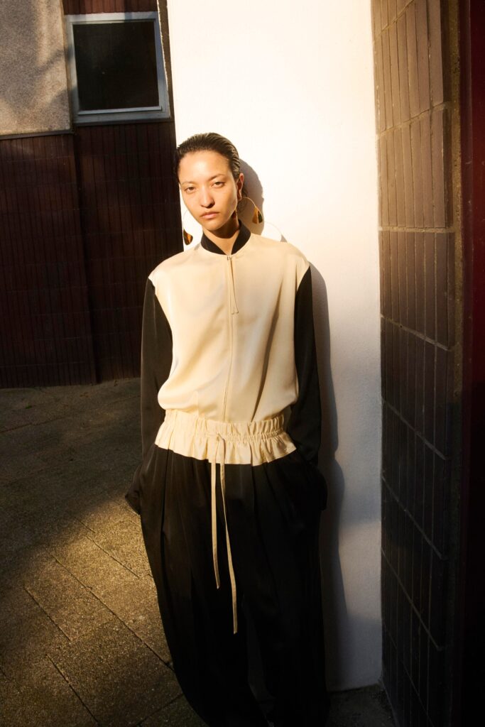 A relaxed beige and black jacket with long sleeves and asymmetric design paired with matching pants.