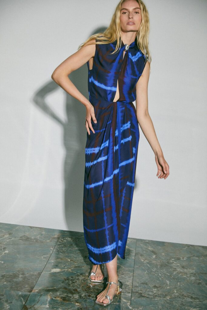 A fitted blue silk dress with a sleeveless design and asymmetric detailing.