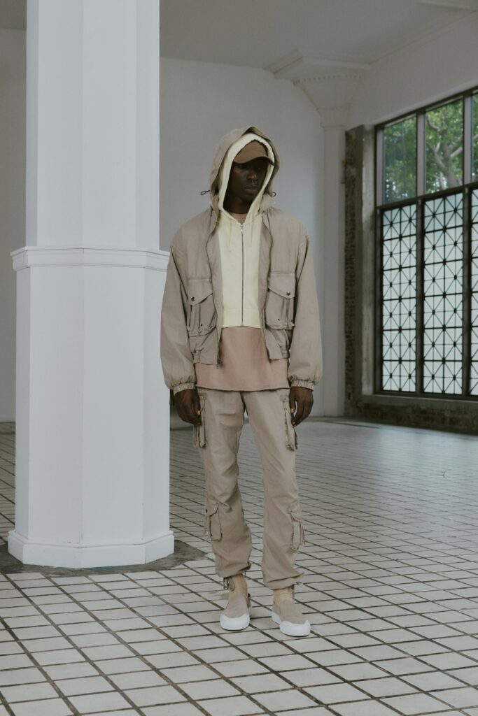 A relaxed beige jacket with a hood and matching pants, featuring a zippered design.
