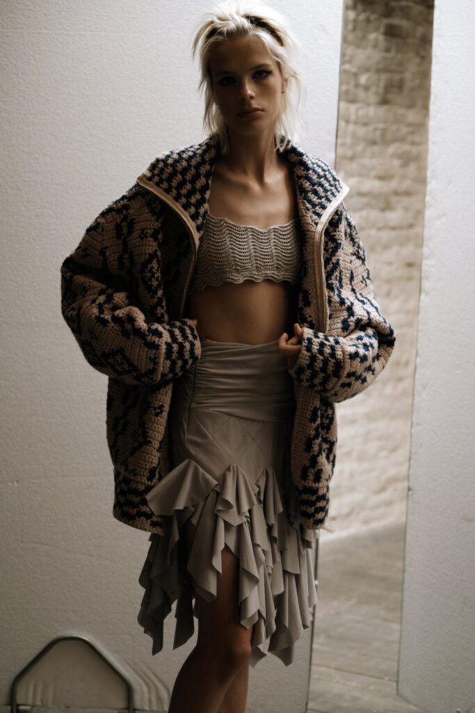 A relaxed beige jacket paired with a ruffled gray skirt, showcasing a unique layered look.