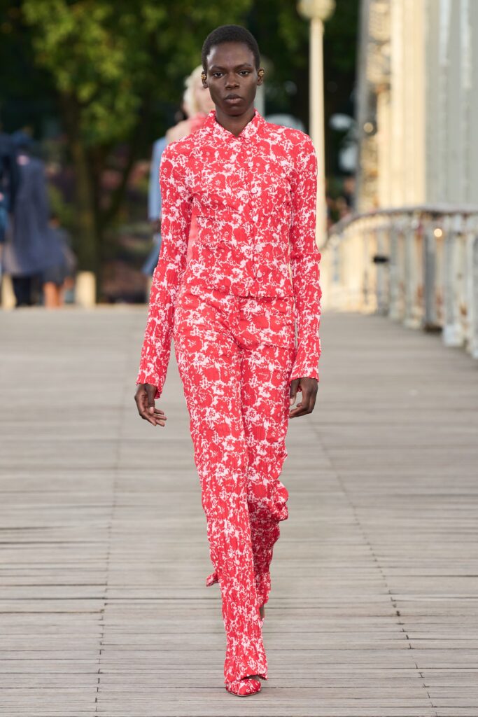 A fitted red floral jumpsuit with long sleeves and a collared neckline.