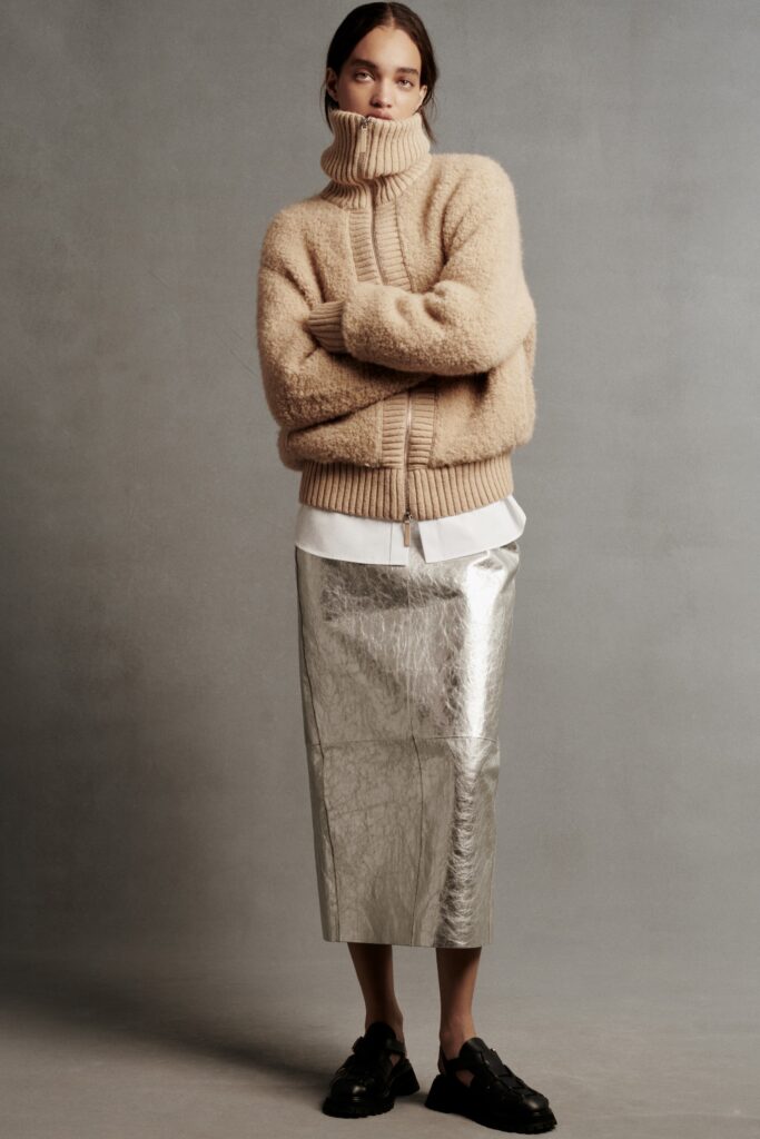 An oversized beige wool sweater paired with a straight-leg metallic silver skirt.