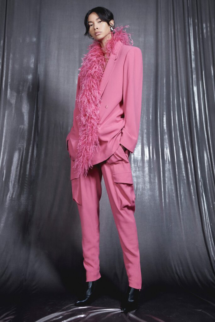 An oversized pink suit with long sleeves and a collared design, featuring a buttoned front.