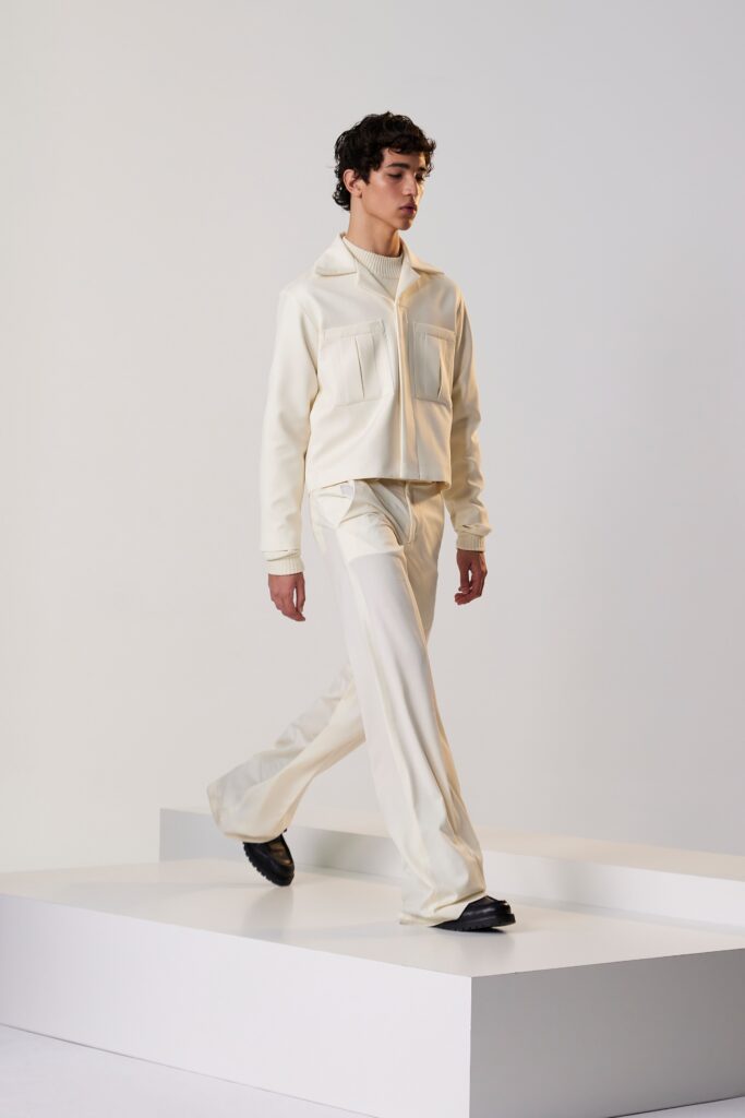 A fitted white cotton jacket with long sleeves and collared design paired with straight-leg pants.