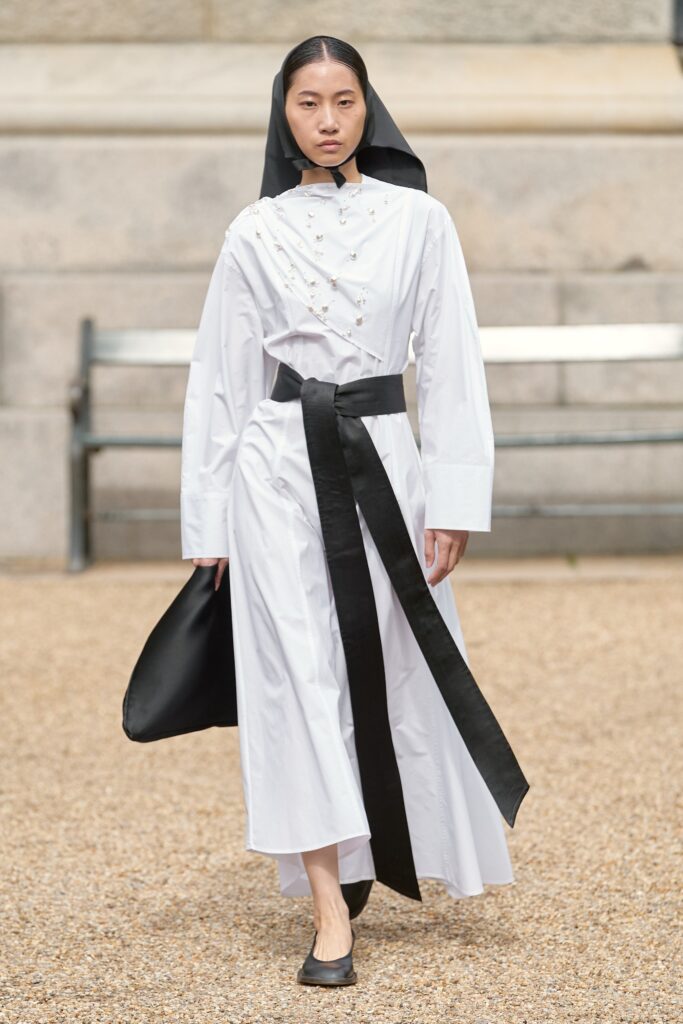 A relaxed white long-sleeve dress with a belted waist and collared neckline.