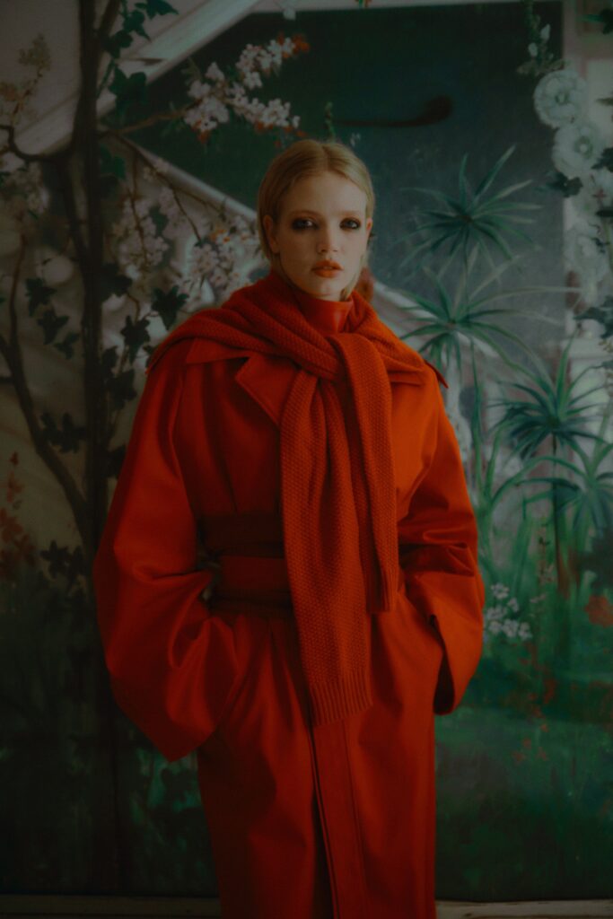 A relaxed red wool coat with long sleeves, a collared neck, and a belted design.