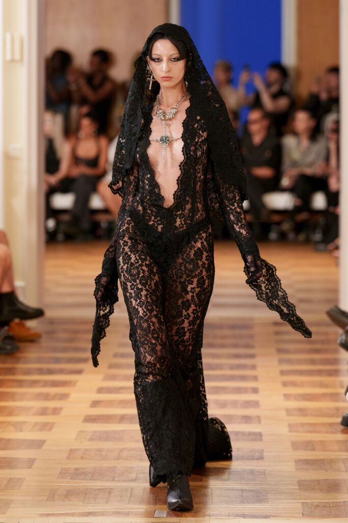 A fitted black lace dress with long sleeves and a deep v-neckline, exuding elegance and allure.