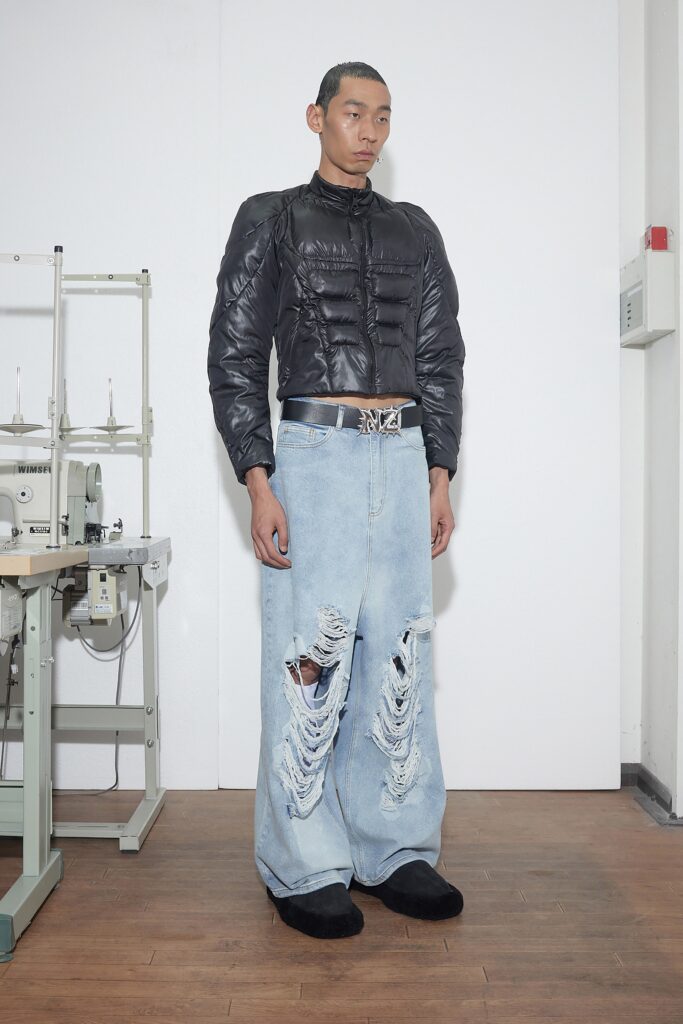 An oversized black jacket paired with distressed blue jeans for a bold streetwear look.