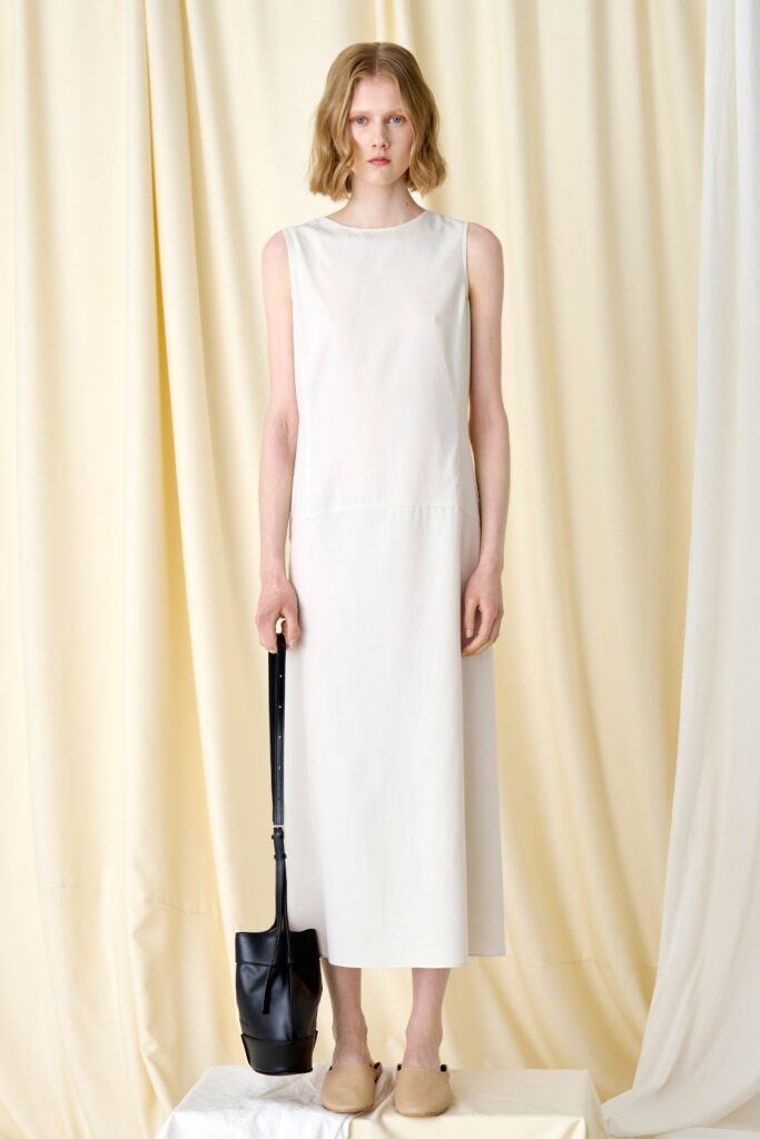 A relaxed white sleeveless dress with a high neckline and straight-leg silhouette.