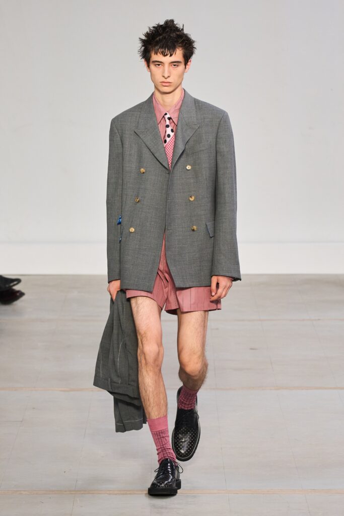 A fitted gray blazer with long sleeves paired with pink shorts, featuring a structured design.