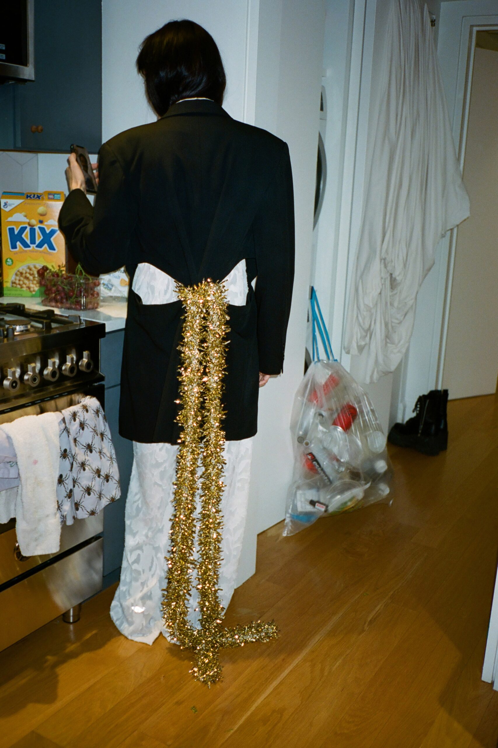 A fitted black blazer paired with white pants, featuring a layered design detail.