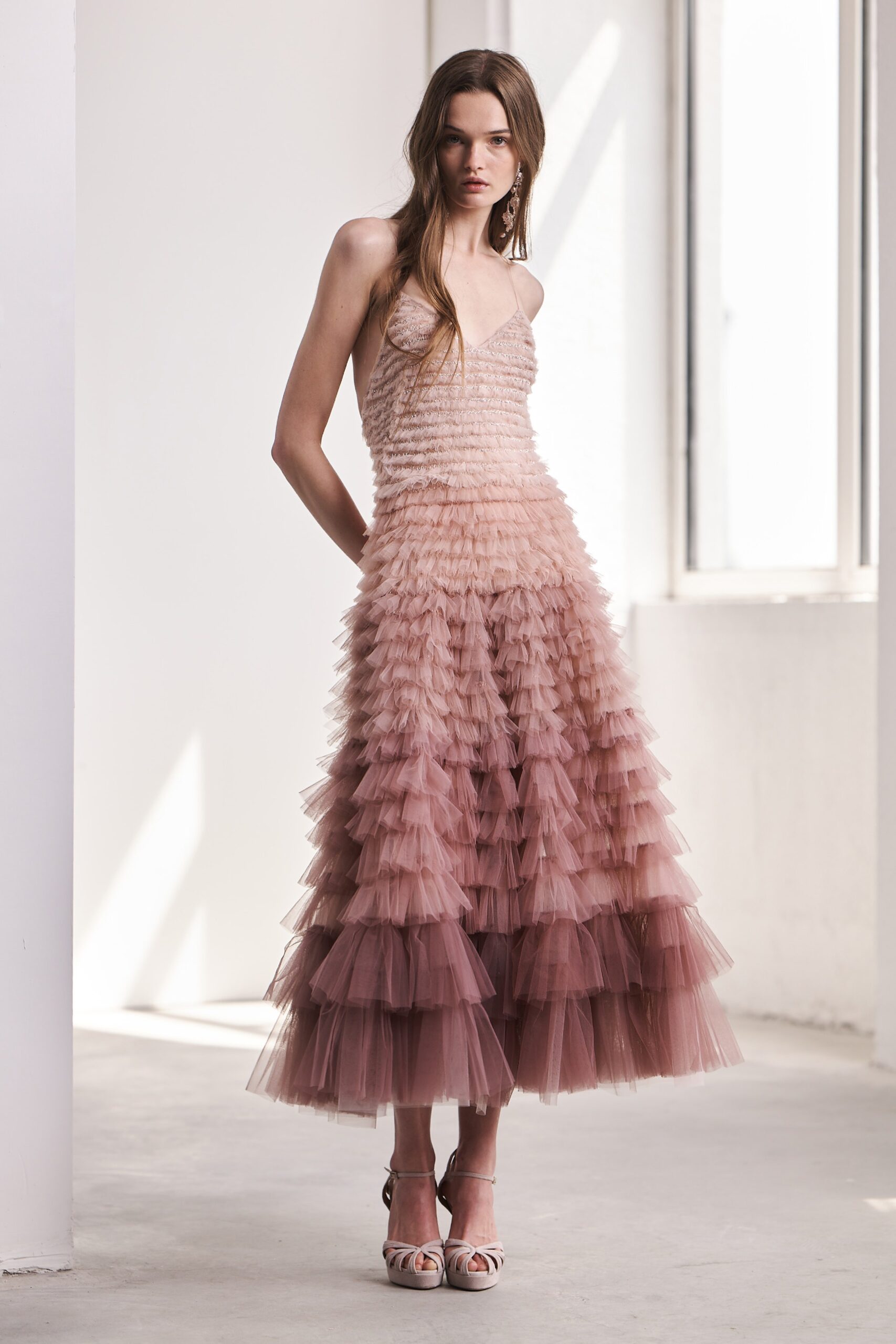 A fitted pink tulle sleeveless dress with a V-neckline and tiered design.