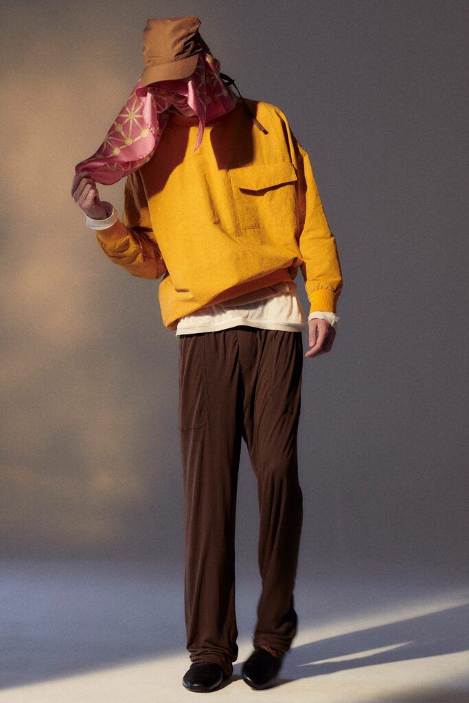A relaxed yellow long-sleeve top paired with brown pants featuring a zippered detail.
