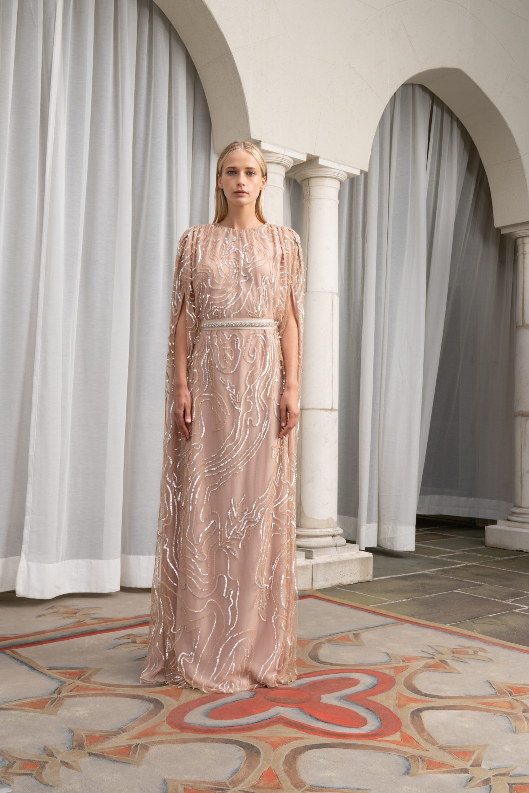 A fitted beige silk gown with long sleeves and intricate embroidery details.