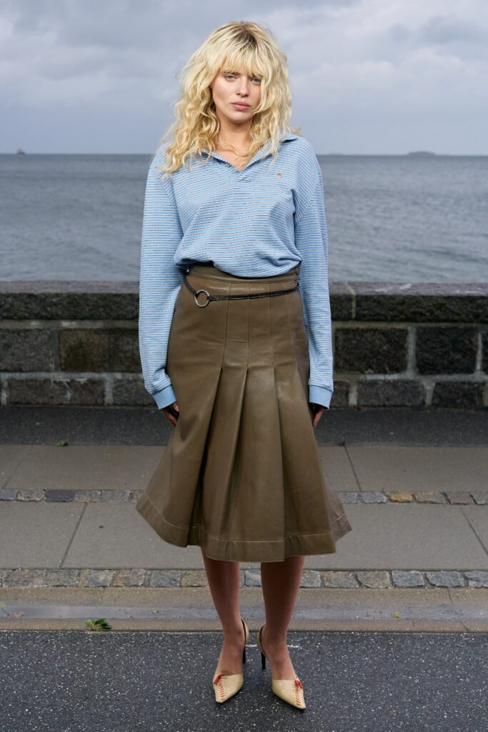 A relaxed blue cotton long-sleeve shirt paired with a pleated brown leather skirt.