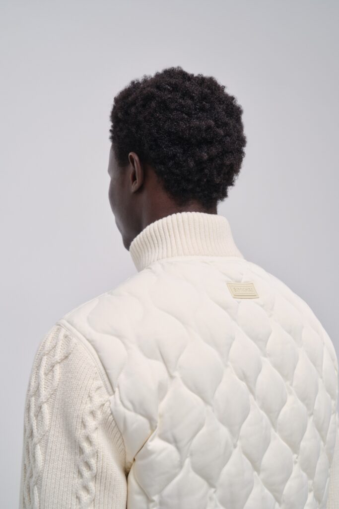A relaxed white quilted jacket paired with a long-sleeve collared sweater.
