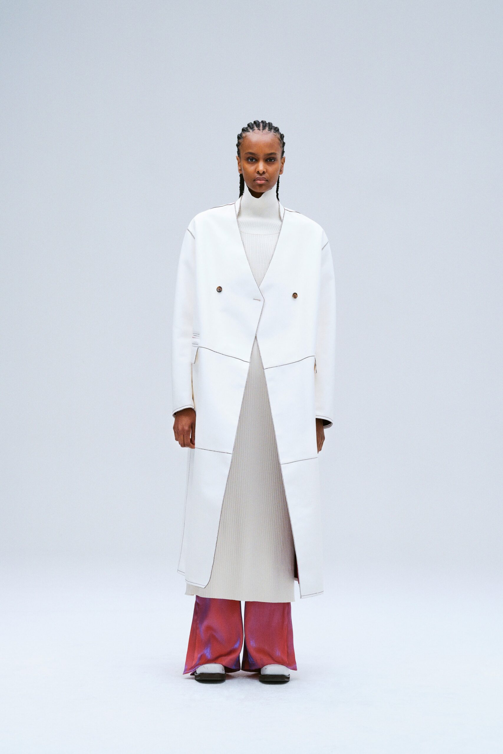 A fitted white coat layered over a pink dress with a collared neckline and asymmetric design.