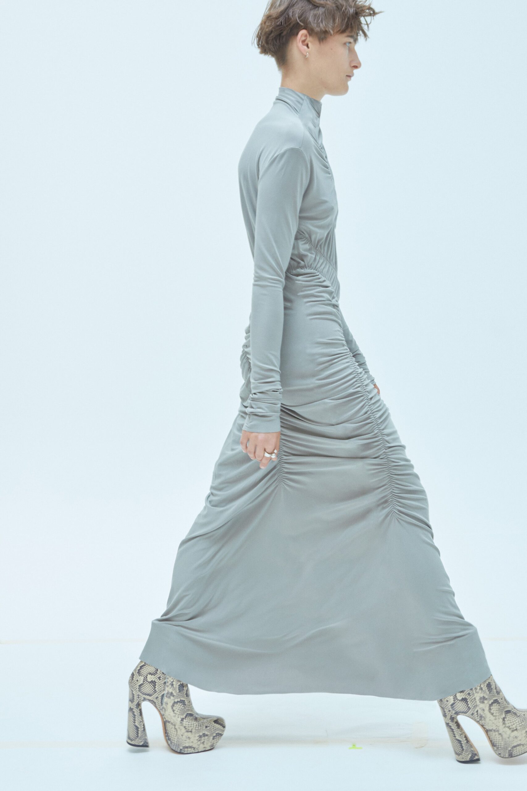 A fitted gray silk dress with long sleeves, high neckline, and ruched maxi silhouette.