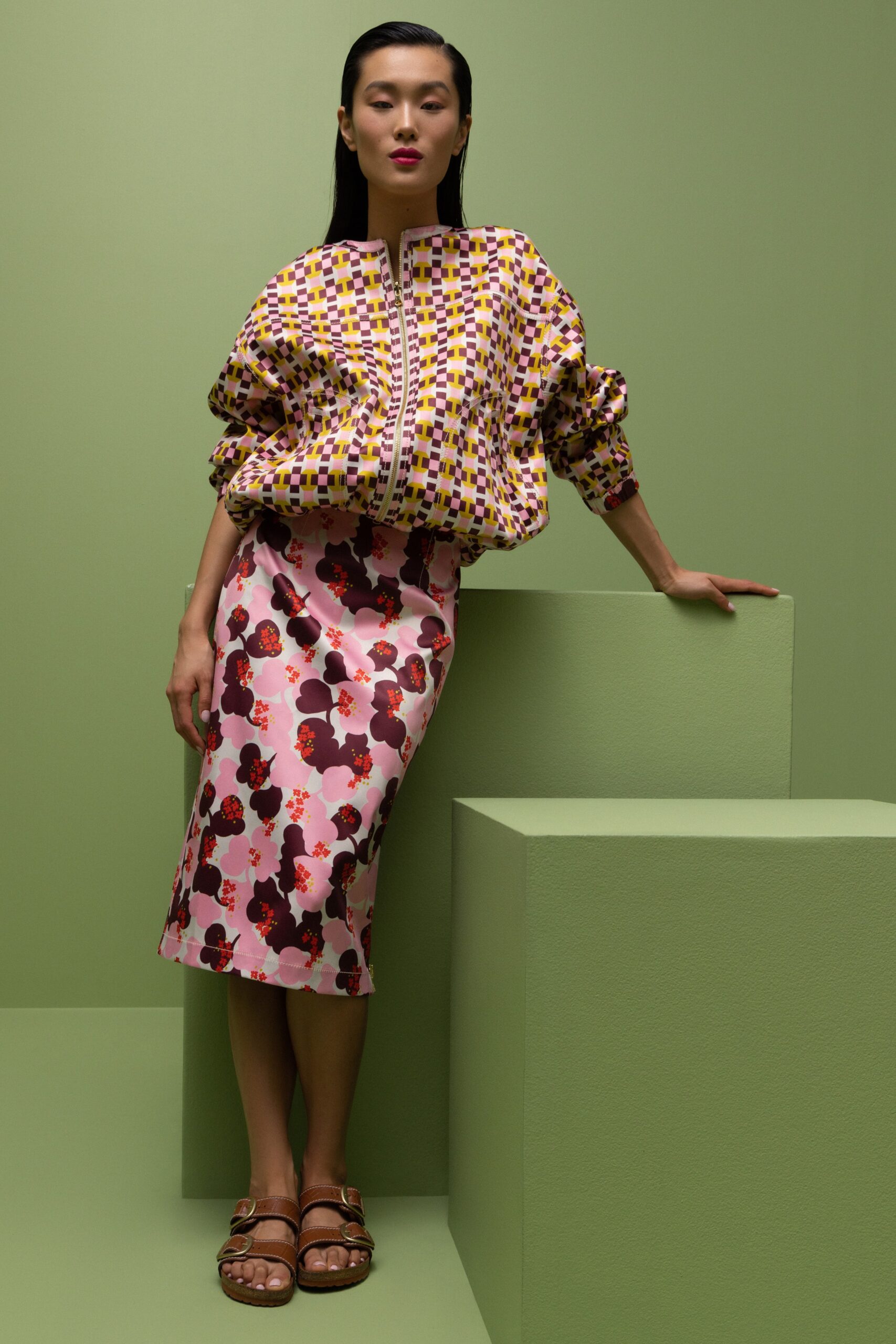 A fitted yellow printed top with long sleeves paired with a pink floral skirt.